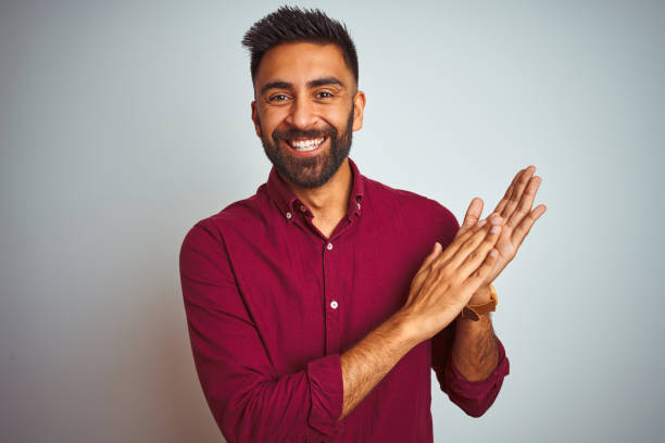 istock Young indian man wearing red elegant shirt standing over isolated grey background clapping and applauding happy and joyful, smiling proud hands together 1205723244
