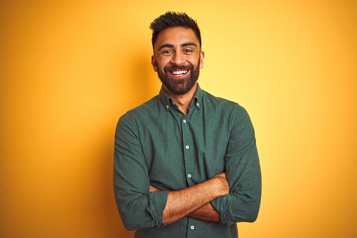 Young indian businessman wearing elegant shirt standing over isolated white background happy face smiling with crossed arms looking at the camera. Positive person.
