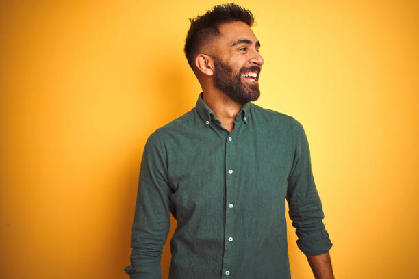 joven hombre de negocios indio con elegante camisa de pie sobre fondo blanco aislado mirando hacia otro lado con la sonrisa en la cara, expresión natural. riendo confiado. - portrait laughing people men fotografías e imágenes de stock