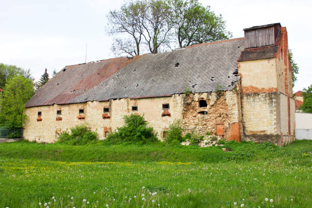 Old brickwork of an old house with broken and brick windows made of various types of bricks and building materials.