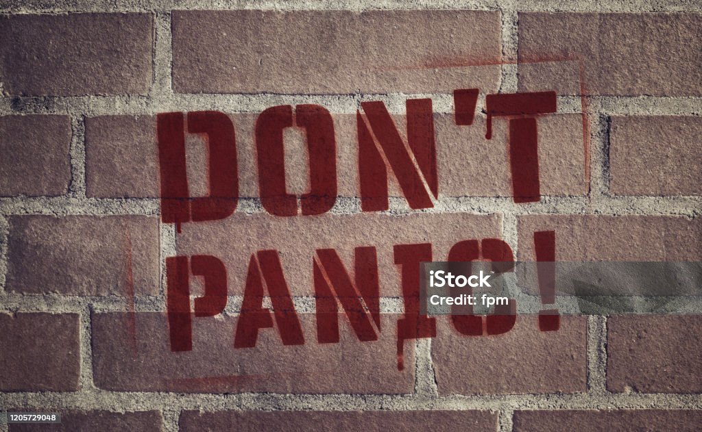 "Don't Panic!" Stencil Spray-Painted on Brick Wall The words "Don't Panic" stenciled in red drippy spray paint onto a brick wall. Terrified Stock Photo