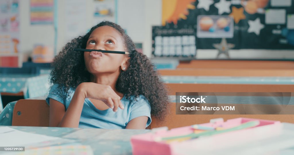 Is it recess yet? Shot of a young girl looking bored while playing at a school desk Attention Deficit Hyperactivity Disorder Stock Photo