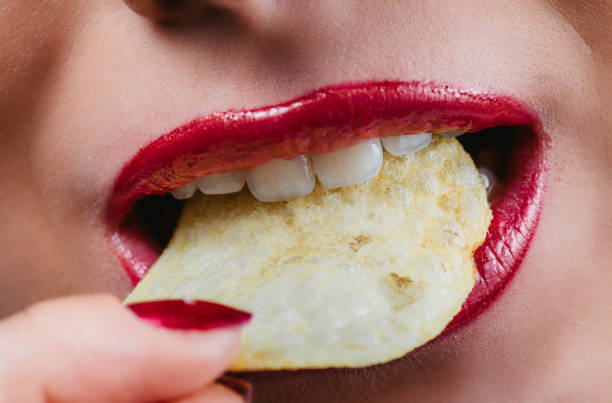istock Beautiful female lips with potato chips 1205729133