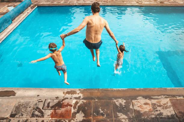 père et fils ayant l’amusement sur la piscine - floating on water swimming pool men water photos et images de collection