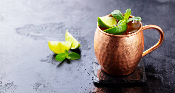 istock Moscow Mules cocktail with ginger beer, vodka, lime and mint. Black background. Copy space. Close up. 1205730884