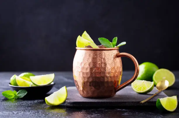 Moscow Mule cocktail with ginger beer, vodka, lime and mint. Dark background. Close up.