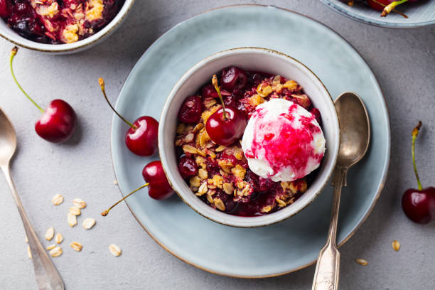 istock Cherry, red berry crumble with ice cream in bowl. Grey stone background. Top view. 1205731607