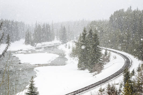 istock Railroad running alongside a mountain river durig a heavy snowfall 1205733132
