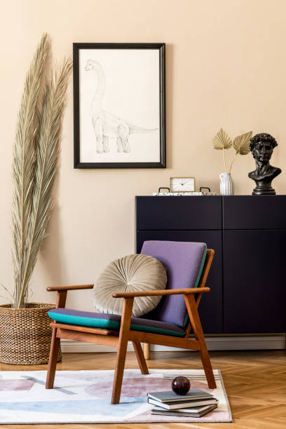 istock Interior design of retro modern living room with black mock up poster frame, blue navy commode, design armchair, palm leafs, books and elegant personal accessories. Stylish home decor. Template. 1205733229