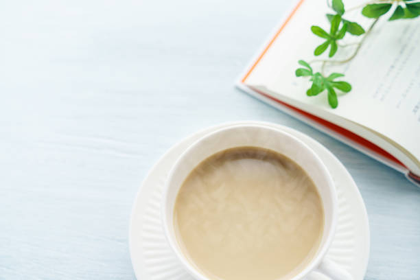 istock Cup of tea with milk and book on wooden table 1205737372