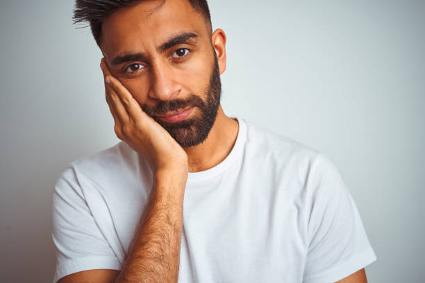 istock Young indian man wearing t-shirt standing over isolated white background thinking looking tired and bored with depression problems with crossed arms. 1205738686