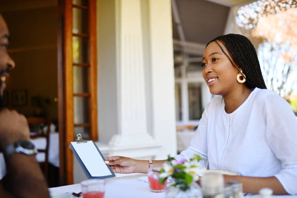 istock Young woman ordering from a menu in a restaurant sitting outdoors on a front stoop 1205739051