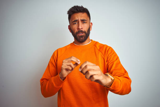 istock Young indian man wearing orange sweater over isolated white background disgusted expression, displeased and fearful doing disgust face because aversion reaction. With hands raised. Annoying concept. 1205739778