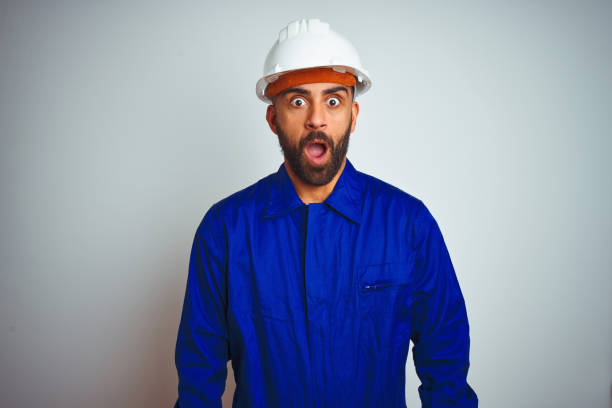 istock Handsome indian worker man wearing uniform and helmet over isolated white background afraid and shocked with surprise expression, fear and excited face. 1205740698