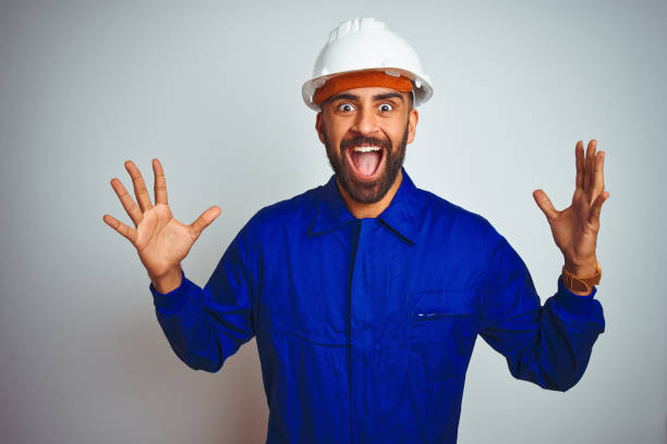 istock Handsome indian worker man wearing uniform and helmet over isolated white background celebrating crazy and amazed for success with arms raised and open eyes screaming excited. Winner concept 1205740934