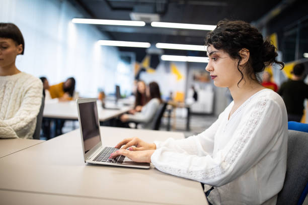 istock Beautiful young woman using laptop at open space workplace 1205741242