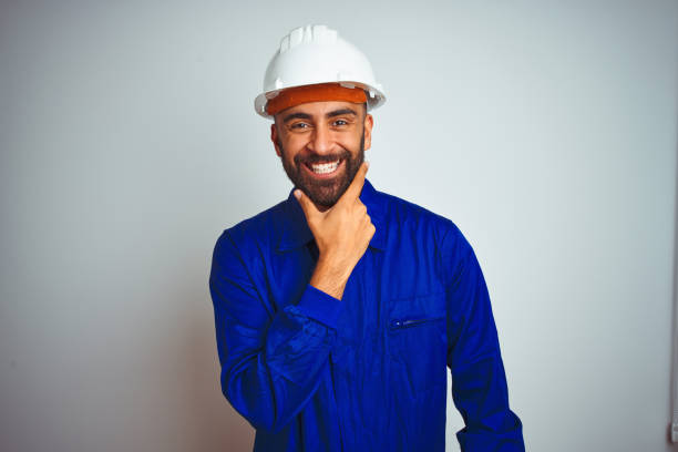 istock Handsome indian worker man wearing uniform and helmet over isolated white background looking confident at the camera smiling with crossed arms and hand raised on chin. Thinking positive. 1205741264