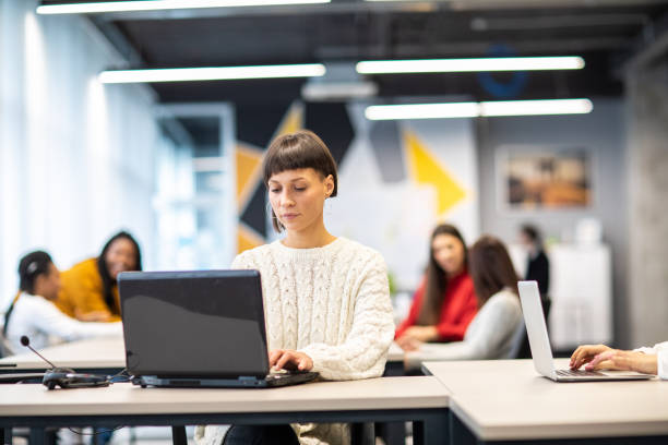 istock Beautiful young woman using laptop at open space workplace 1205741439