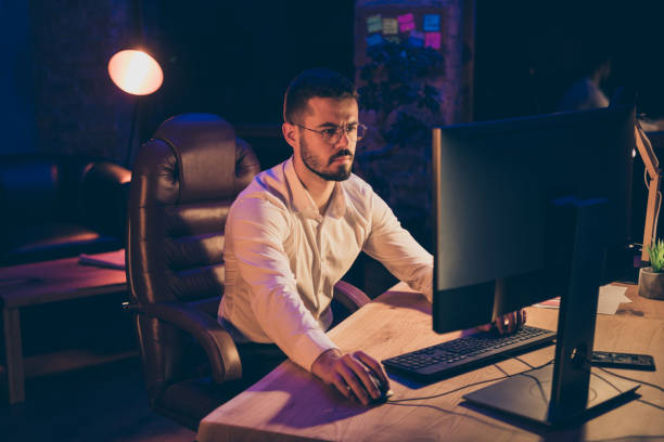 istock Portrait of focused marketer man sit table work on computer search statistics for his company development want finish presentation for partnership conference type email in dark evening loft 1205742665