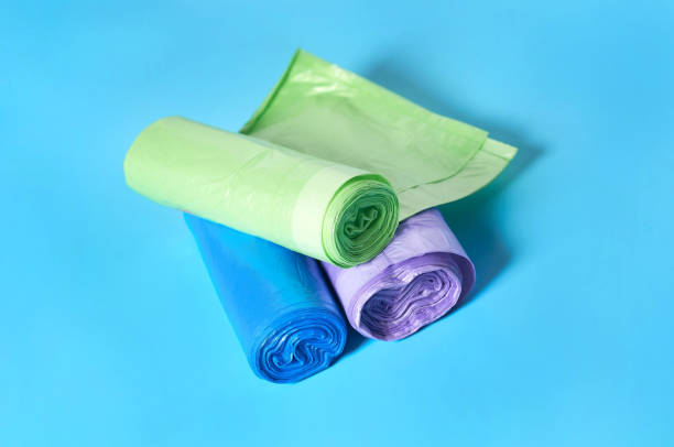 istock Scattered rolls of disposable plastic garbage bag on blue background. Close-up 1205743352