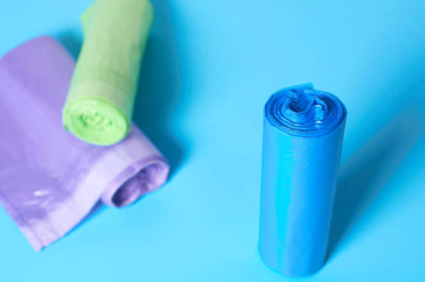 istock Scattered rolls of disposable plastic garbage bag on blue background. Close-up 1205743407