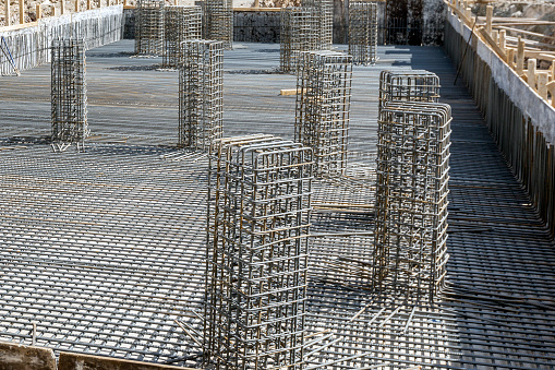 View of a tied rebar beam cage before casting concrete. This will be embedded inside cast concrete to increase its tensile strength. Rebar (short for reinforcing bar), known when massed as reinforcing steel or reinforcement steel.