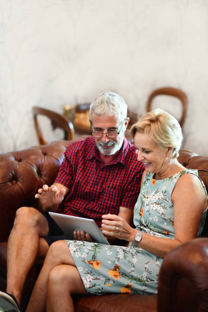 istock Senior Couple sitting relaxing indoors browsing on a digital tablet 1205744955