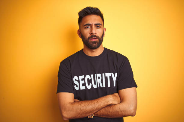 istock Arab indian hispanic safeguard man wearing security uniform over isolated yellow background skeptic and nervous, disapproving expression on face with crossed arms. Negative person. 1205745149