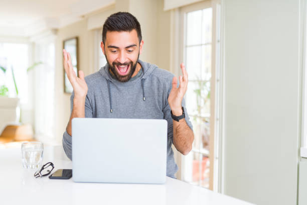 istock Handsome hispanic man working using computer laptop very happy and excited, winner expression celebrating victory screaming with big smile and raised hands 1205747426