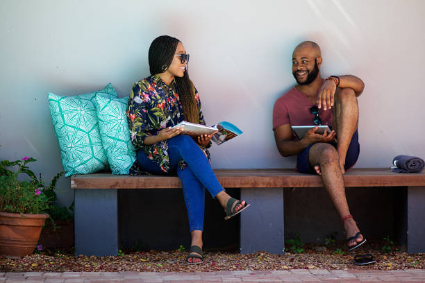 Couple Sitting next to the pool relaxing on a bench reading and smiling