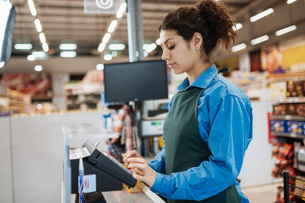 Female Latina employee in supermarket Working in modern supermarket in Latin America cashier photos stock pictures, royalty-free photos & images