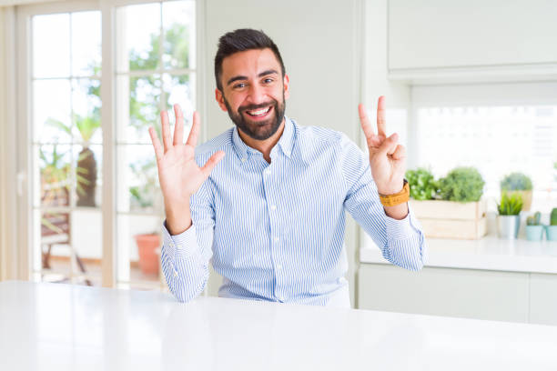 istock Handsome hispanic business man showing and pointing up with fingers number seven while smiling confident and happy. 1205748845