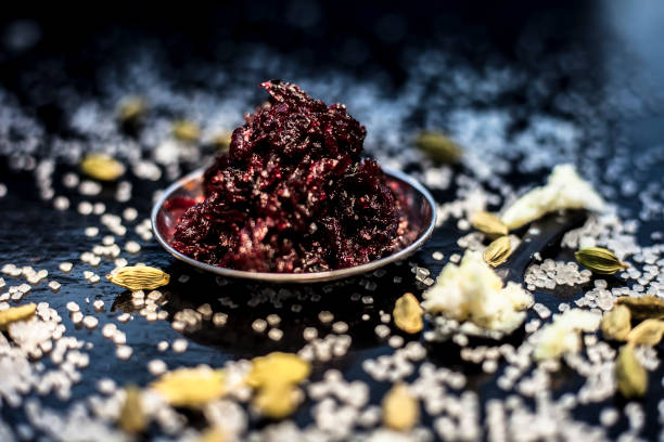 Close up of fresh beetroot halwa or beet ka halwa in a plate with some spread sugar crystals and elaichi or green cardamom. Horizontal shot.