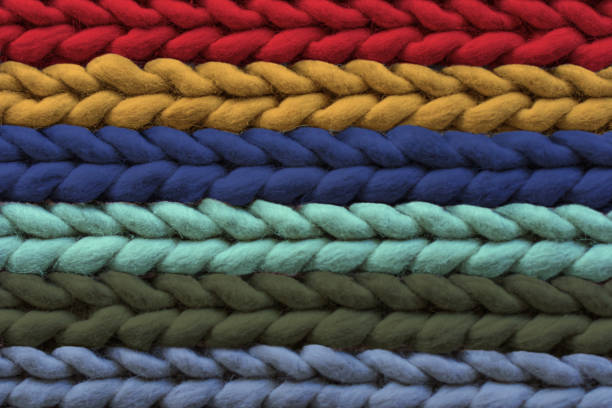 Texture of warm multi-colored woolen rug, background. Pigtail pattern, soft focus.
