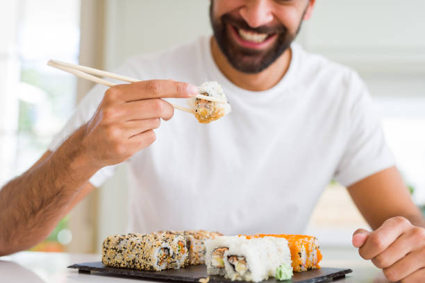 istock Handsome man smiling happy enjoying eating fresh colorful asian sushi using chopsticks 1205751366