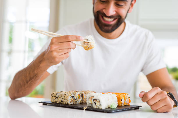 istock Handsome man smiling happy enjoying eating fresh colorful asian sushi using chopsticks 1205751367