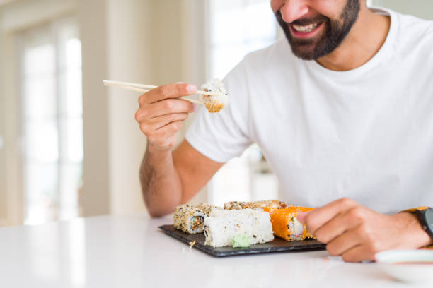 istock Handsome man smiling happy enjoying eating fresh colorful asian sushi using chopsticks 1205751370