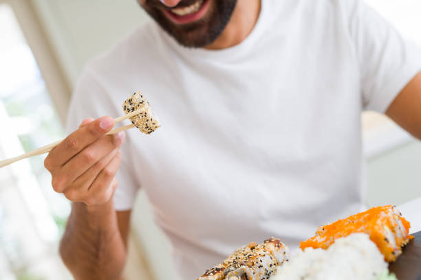 istock Handsome man smiling happy enjoying eating fresh colorful asian sushi using chopsticks 1205751375