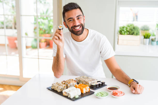 istock Handsome man smiling happy enjoying eating fresh colorful asian sushi using chopsticks 1205751383