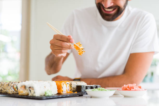istock Handsome man smiling happy enjoying eating fresh colorful asian sushi using chopsticks 1205751428