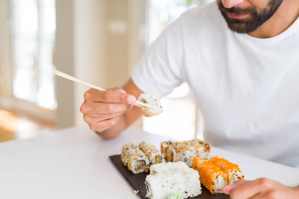 istock Handsome man smiling happy enjoying eating fresh colorful asian sushi using chopsticks 1205751564