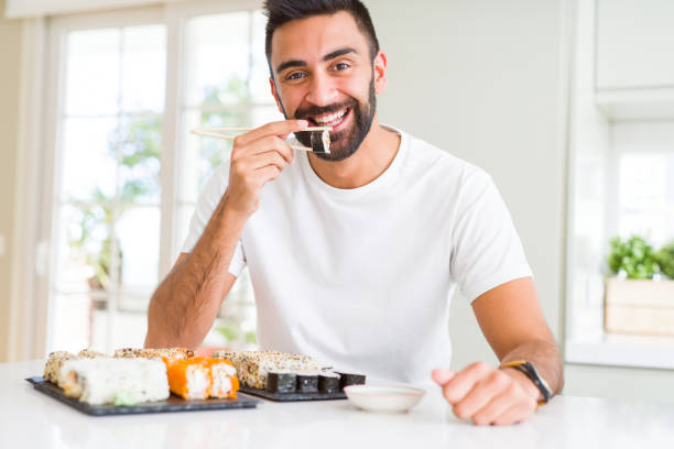 istock Handsome man smiling happy enjoying eating fresh colorful asian sushi using chopsticks 1205751568