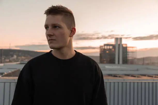 Photo of Young Man standing on Urban Rooftop at Sunset Portrait