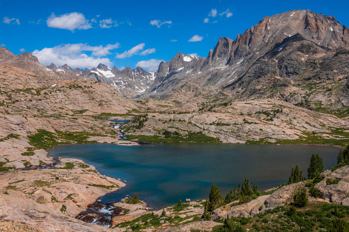 A panoramic view of the Wyoming Wind River Range Titcomb Basin surrounded by high mountain peaks and glaciers with lakes and streams.