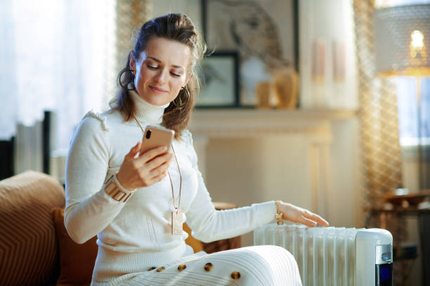 woman near radiator using smartphone app for temperature control