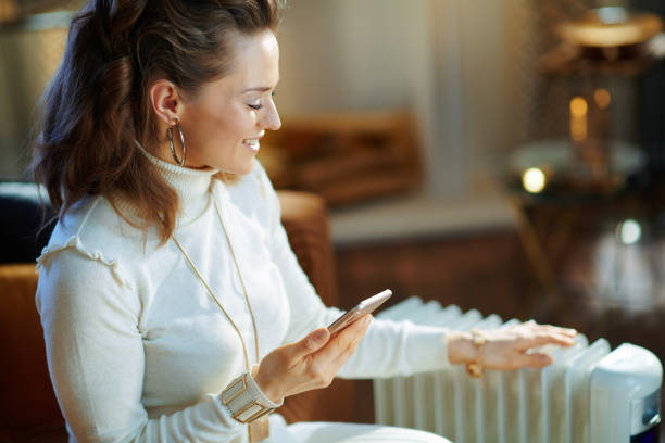 istock woman near radiator using smartphone app for temperature control 1205756103