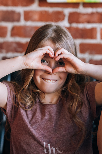 Cute young girl making a heart shape with her hands.