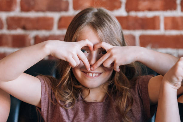 istock Young Girl Making Heart Shape Symbol With Her Hands 1205756320