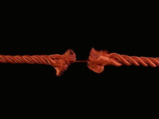 istock The torn rope is about to break, a black background. The rope is held on one thread. Concept: life in the balance. 1205757548