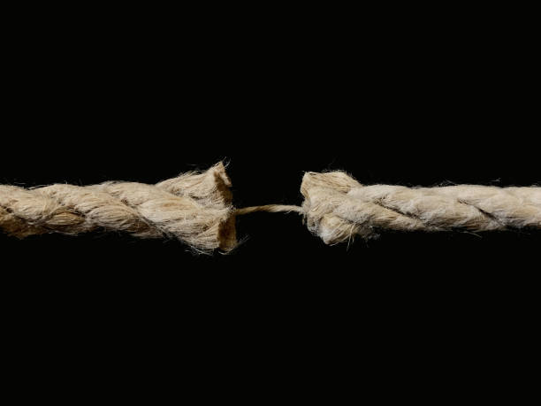 istock The torn rope is about to break, a black background. The rope is held on one thread. Concept: life in the balance. 1205757552